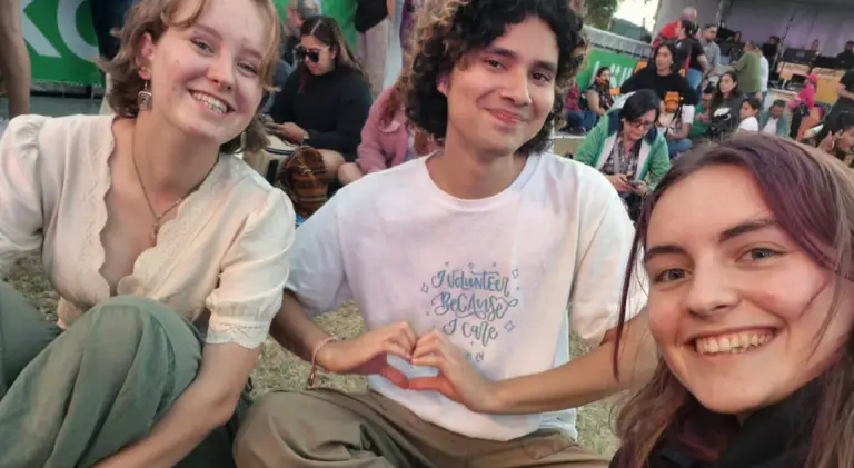 Aldo Membreño Brenes, leader of the Greentalist Orientation Commission, shares a heart-hand gesture with two fellow volunteers at an outdoor community event.
